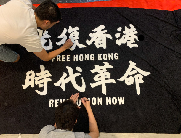 Two people hand-painting the protest banner