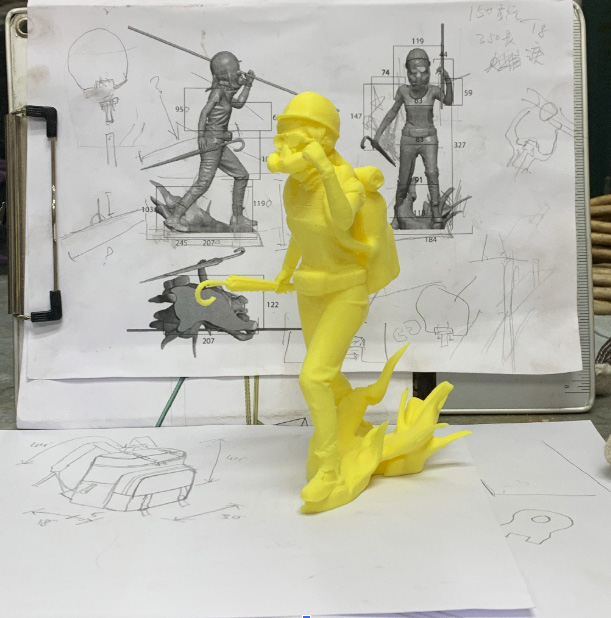 A yellow prototype of the statue in front of the design proposals